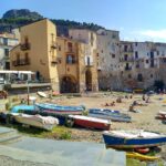 Vista panoramica di una spiaggia deserta in Sicilia, circondata da scogliere e acque cristalline.