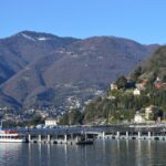 Vista panoramica del Lago di Como con ville storiche e battelli in navigazione a marzo.