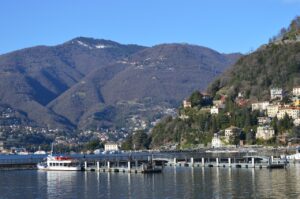 Vista panoramica del Lago di Como con ville storiche e battelli in navigazione a marzo.