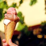 Gelato artigianale delizioso in un cono, tipico della Puglia, con sfondo di un pittoresco paese pugliese.