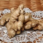 Zenzero fresco e radice di zenzero su uno sfondo di legno, simbolo di rimedi naturali per il colesterolo.