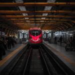 Treno che attraversa un paesaggio italiano con città d'arte sullo sfondo, simbolo di viaggi sostenibili.