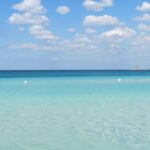Spiaggia del Salento con sabbia bianca e acqua cristallina, simile ai Caraibi, in una giornata di sole di marzo.